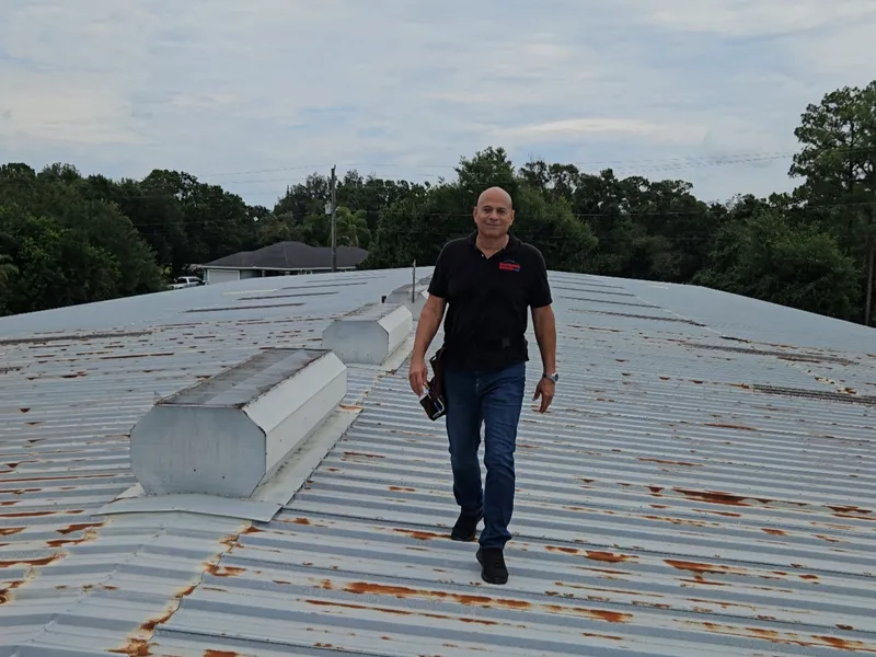 Ron Hogan inspecting a weathered metal roof on a Florida job site