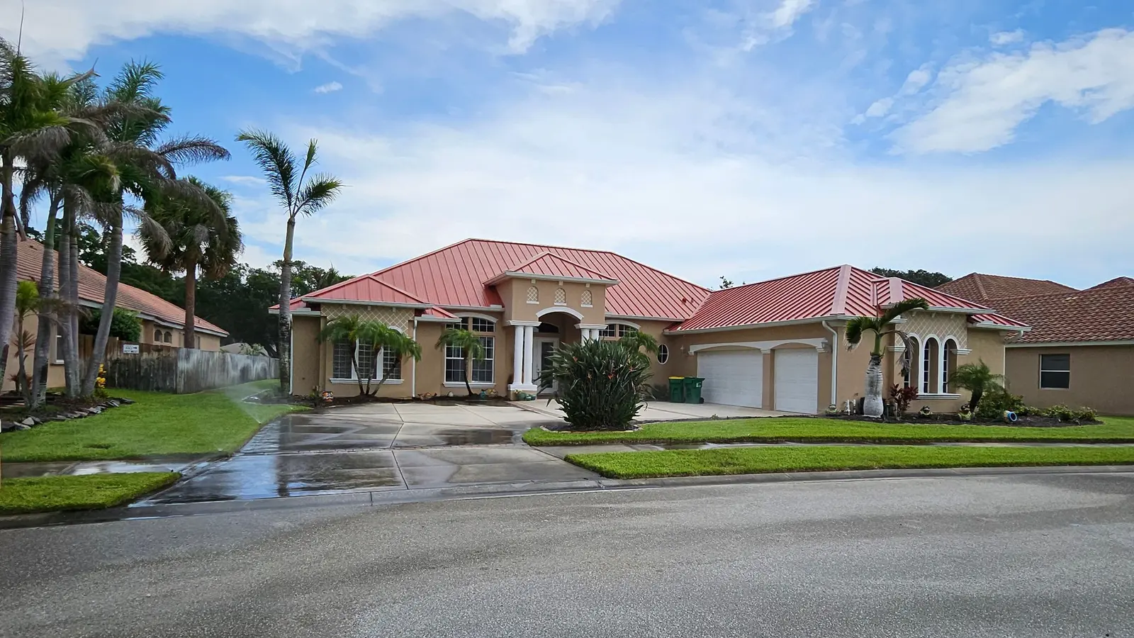 Red standing seam metal roof on a stucco home with palm trees in Merritt Island, Florida